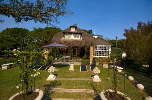 Casa con jardín con sillas y sombrilla en Forest Hall Guest House, en Port Elizabeth