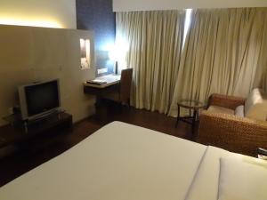 a hotel room with a bed and a desk and a television at Hotel Satkar Residency in Thane