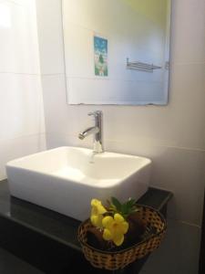 a white sink and a basket with yellow flowers on a counter at Kiki Coconut Beach Resort in Phu Quoc