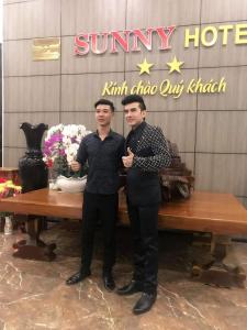 dos hombres están parados frente a una mesa en Sunny Hotel, en Phan Rang
