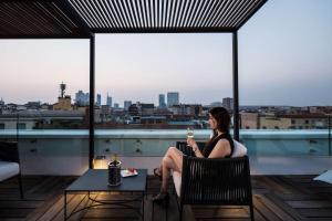 una mujer sentada en un balcón con una copa de vino en Best Western Hotel City en Milán