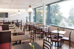 a restaurant with tables and chairs and large windows at Caritas Tagungszentrum in Freiburg im Breisgau