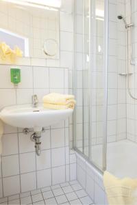 La salle de bains blanche est pourvue d'un lavabo et d'une douche. dans l'établissement Caritas Tagungszentrum, à Fribourg-en-Brisgau