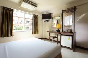 a bedroom with a bed and a desk and a mirror at Rambuttri Village Plaza in Bangkok