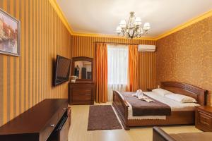 a bedroom with a bed and a dresser and a television at Deja Vu Apart-Hotel in Pyatigorsk