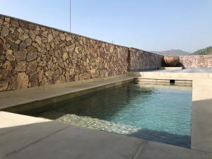 a swimming pool in front of a stone wall at Jai Villa Homestay in Udaipur