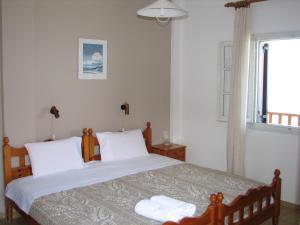 sypialnia z łóżkiem z białą pościelą i oknem w obiekcie MARIA Studios & Apartments w mieście Agios Ioannis Pelio