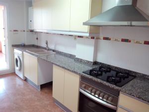 a kitchen with a sink and a stove top oven at Apartmento playa Almarda. Piscina&Parking in Almarda