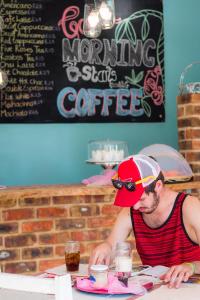 a man sitting at a table in a coffee shop at Pili Pili Beach Cabanas in Sedgefield