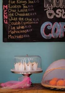 a plate of cupcakes on a table with a sign at Pili Pili Beach Cabanas in Sedgefield