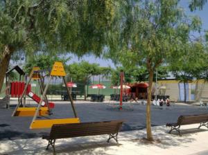 a playground with two benches and a swing set at Apartmento playa Almarda. Piscina&Parking in Almarda