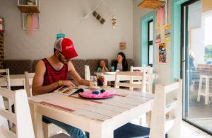 a man sitting at a table in a restaurant at Pili Pili Beach Cabanas in Sedgefield