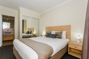 a bedroom with a large bed and a bathroom at Perth Ascot Central Apartment Hotel Official in Perth