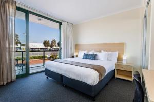 a hotel room with a bed and a balcony at Perth Ascot Central Apartment Hotel Official in Perth