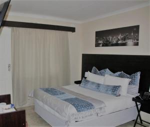 una camera da letto con un grande letto con cuscini blu e bianchi di Savannah Guest House a Polokwane