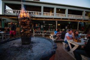 a fire pit at a restaurant with people sitting at tables at Pili Pili Beach Cabanas in Sedgefield