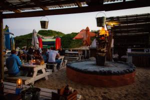 a group of people sitting at tables in a restaurant at Pili Pili Beach Cabanas in Sedgefield