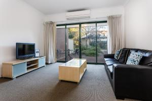 a living room with a couch and a tv at Perth Ascot Central Apartment Hotel Official in Perth