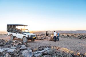 a group of people standing around a picnic table in the desert at Fish River Lodge in Ariamab