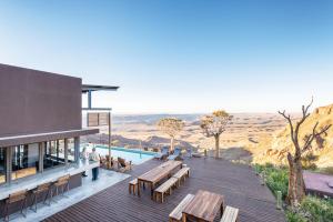 a building with a deck with benches and a pool at Fish River Lodge in Ariamab