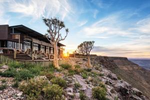 una casa en la cima de una montaña con la puesta de sol en Fish River Lodge, en Ariamab