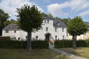 een groot wit huis met twee bomen ervoor bij Parkhotel Ebersdorf in Saalburg