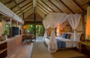 a bedroom with a bed with a canopy at Jeeva Klui Resort in Senggigi