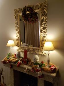 een spiegel boven een open haard met kerstversiering erop bij Paola's Apartment in Belgirate