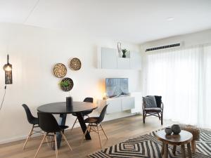 a white living room with a table and chairs at BizStay Helena at Sea Apartments in Scheveningen