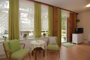 ein Wohnzimmer mit einem Tisch, Stühlen und Fenstern in der Unterkunft Parkhotel Ebersdorf in Saalburg