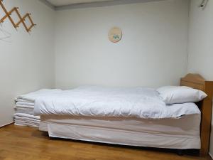 a bed with white sheets and a clock on the wall at White House in Sokcho +31 photos