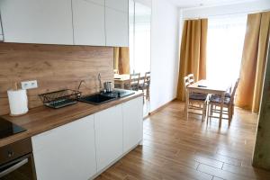 a kitchen with white cabinets and a wooden floor at Simar in Czeladź