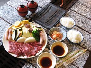 a plate of food with meat and other foods and dipping sauces at 森林公園スイス村 青少年 山の家 in Kyotango