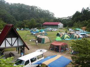 a group of tents and a truck parked in a field at 森林公園スイス村 青少年 山の家 in Kyotango