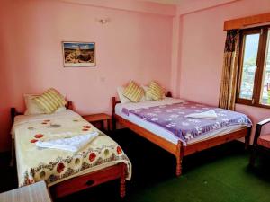 2 letti in una camera con pareti rosa e finestra di Hotel Lotus Inn a Pokhara Altre 24 foto