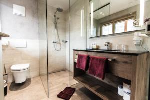 a bathroom with a toilet and a glass shower at Aktivhotel Tuxerhof in Zell am Ziller