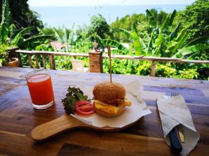 a sandwich on a wooden table with a glass of juice at Blanco Hideout Railay - Youth Hostel 18 to 35 Only in Railay Beach