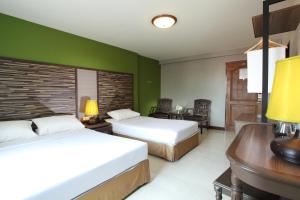 a hotel room with two beds and a desk at Rambuttri Village Plaza in Bangkok