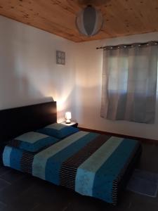 a bedroom with a bed with a blue comforter and a window at R'Marine439 locations saisonnières in La Marine