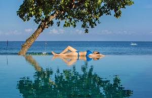 a woman laying in the water next to the ocean at Jeeva Klui Resort in Senggigi