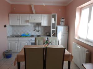 una cocina con armarios blancos y una mesa con sillas. en Villa Apolonija, en Zadar