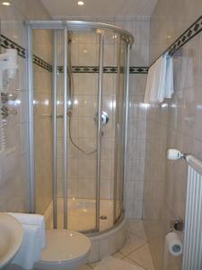 y baño con ducha, aseo y lavamanos. en Hotel Die Post, en Offenbach