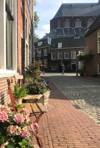 a cobblestone street with two benches and a building at De Pelgrimsplaats in Leiden