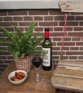 una bottiglia di vino, una ciotola di cibo e un bicchiere di De Pelgrimsplaats a Leida