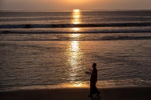 a man walking on the beach at sunset at Jeeva Klui Resort in Senggigi