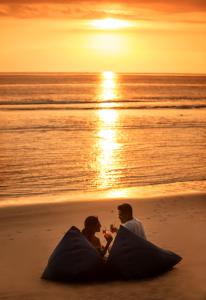 two people sitting on the beach at sunset at Jeeva Klui Resort in Senggigi