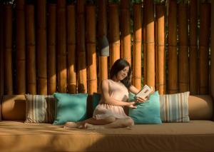 a woman sitting on a couch reading a book at Jeeva Klui Resort in Senggigi