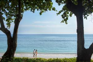 two people walking on the beach near the ocean at Jeeva Klui Resort in Senggigi