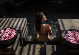 a woman in a bathing suit sitting in the water at Jeeva Klui Resort in Senggigi