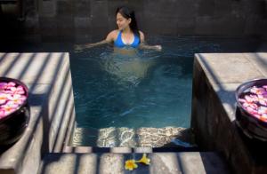 a woman in a pool of water next to some food at Jeeva Klui Resort in Senggigi